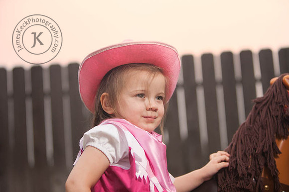 Girl Dressed as Cowgirl Standing Next to Toy Horse