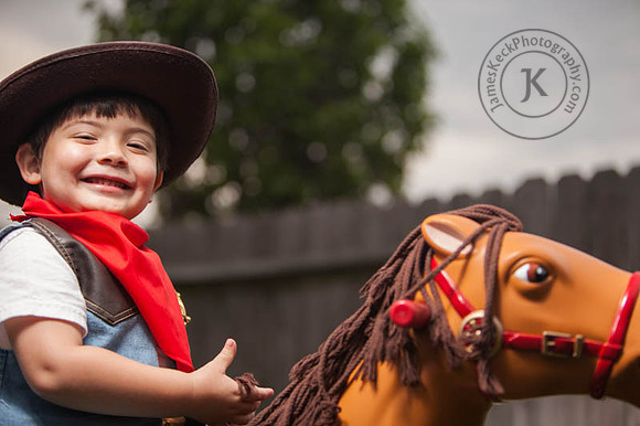 Smiling Boy Dressed as a Cowboy Riding a Toy Horse