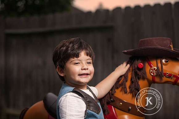 Boy Dressed as Cowboy Putting Hat on Toy Horse