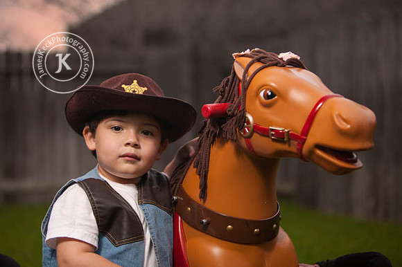 Boy Dressed as Cowboy Standing Next to Toy Horse