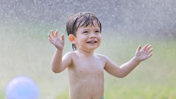 Portrait of Toddler Playing in the Sprinkler