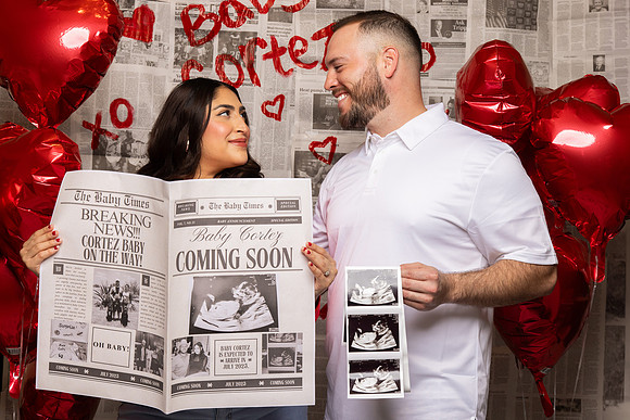 Couple Holding Newspaper and Baby Photos