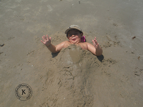 Little Boy Covered in Sand on the Beach