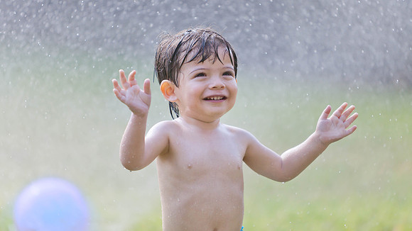 Boy Playing in Sprinkler Portrait